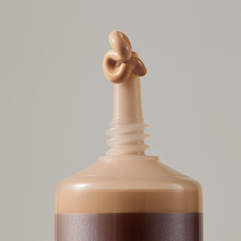 Macro view of TimeWise Luminous 3D Foundation needle-nose applicator dispensing Medium 2 shade