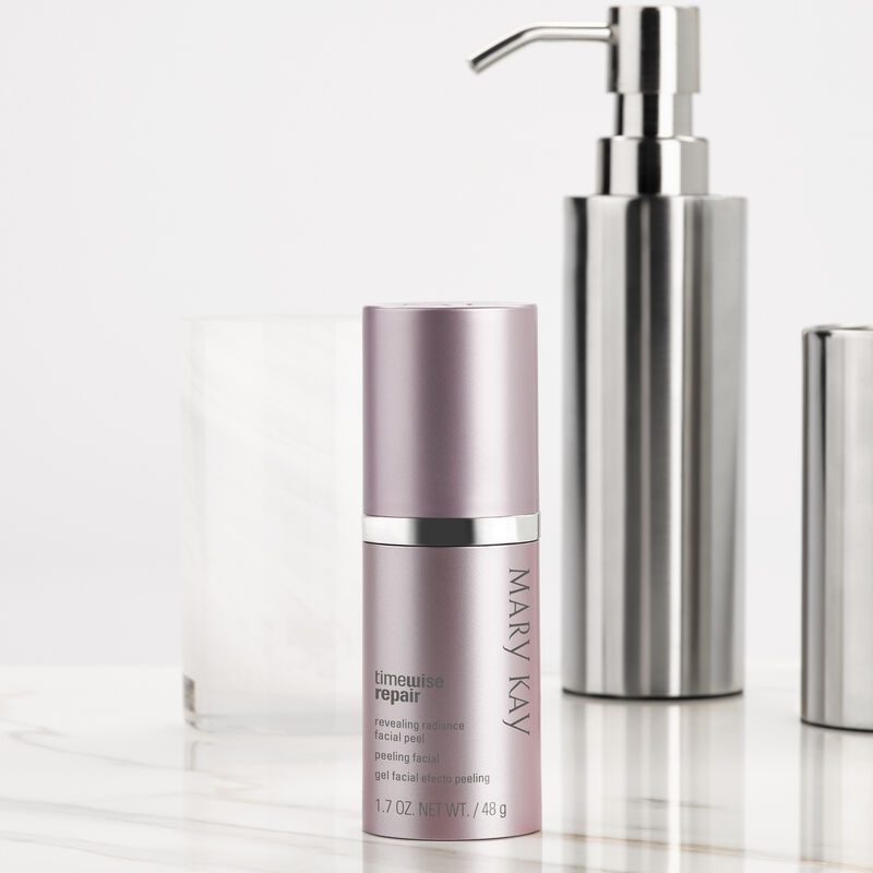 Bottle of TimeWise Repair Revealing Radiance Facial Peel from Mary Kay with cap on styled with silver and white marble bathroom accessories.