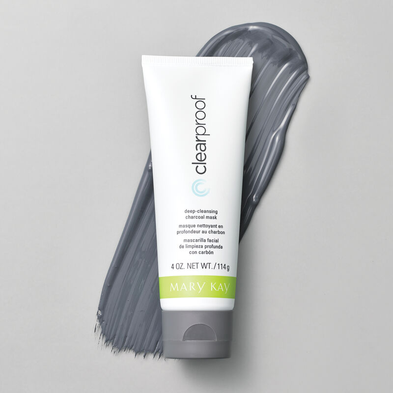 A bottle of Mary Kay Clear Proof Deep Cleansing Charcoal Mask rests atop a smear of its creamy grey contents. 