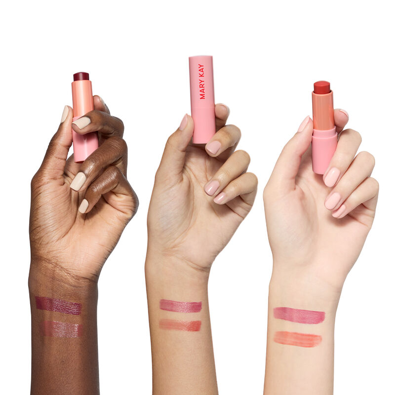Swatches of both shades from the limited-edition Mary Kay Tinted Lip Balm on deep, medium and light skin-toned arms against white background with unca