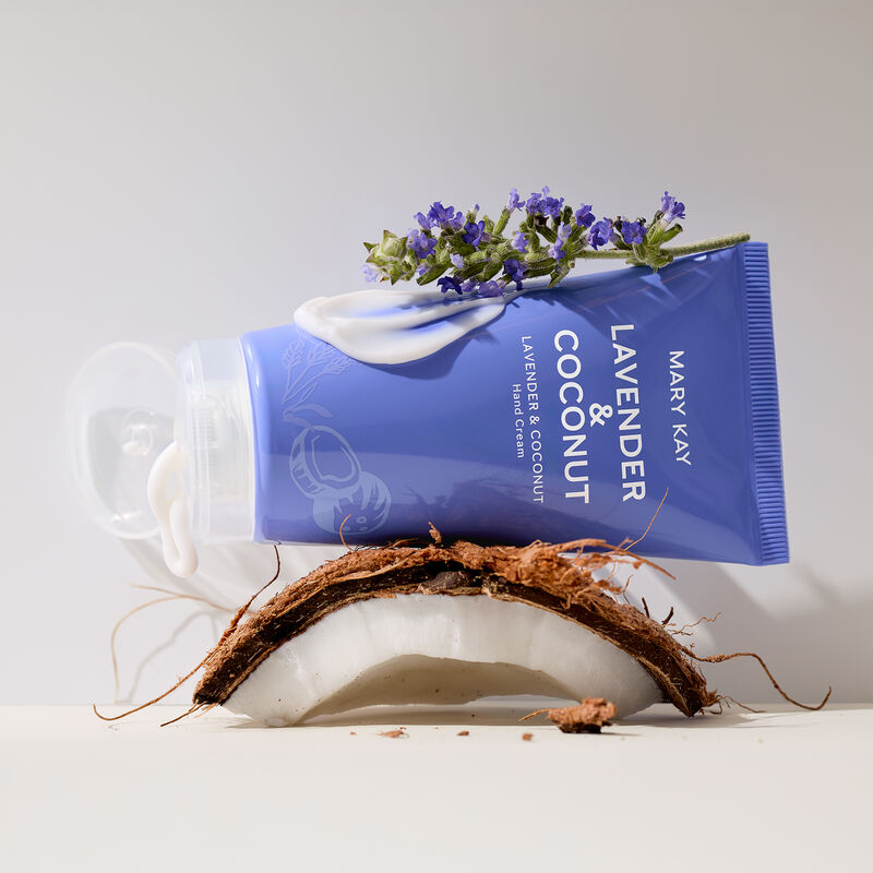 Purple hand cream tube open with product gently squeezed out, balancing on a slice of coconut and sprig of lavender.&nbsp; image number null