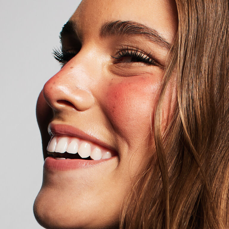 Close-up of smiling model with curly hair wearing the Glass Lips look
