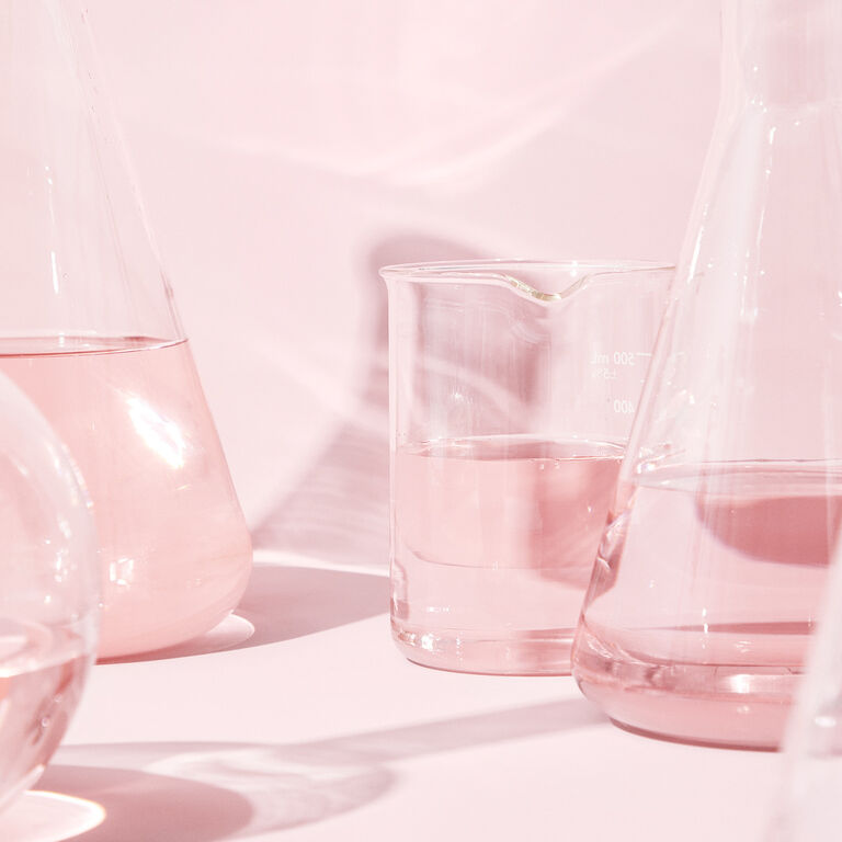 Scientific glass beakers on a pink background