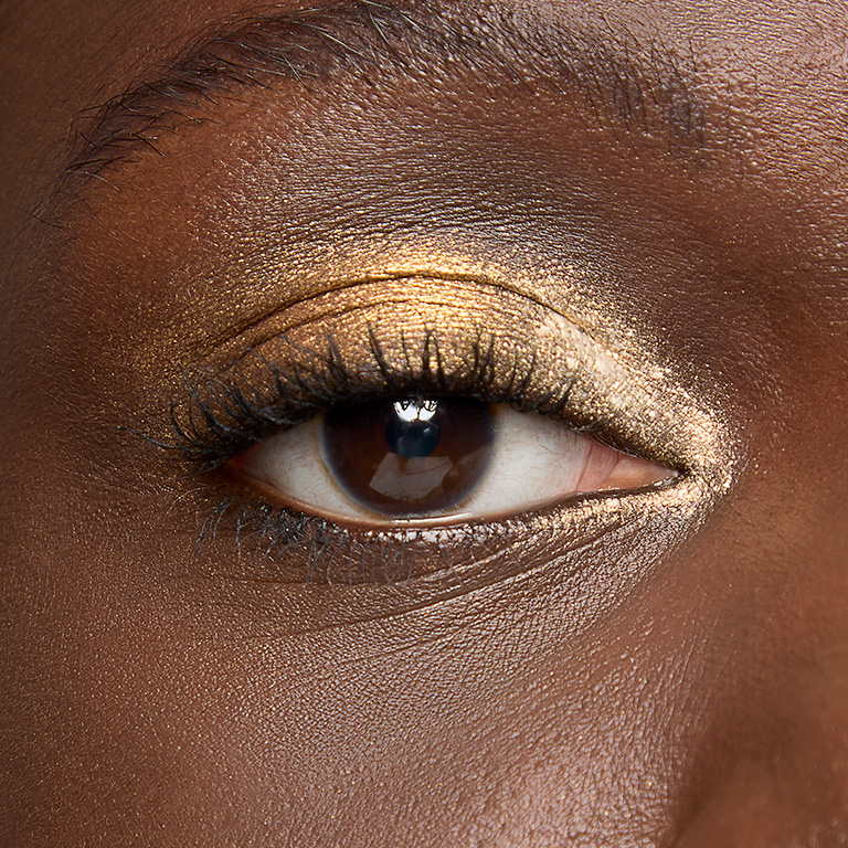 Woman with deep skin tone wearing a gold eyeshadow look